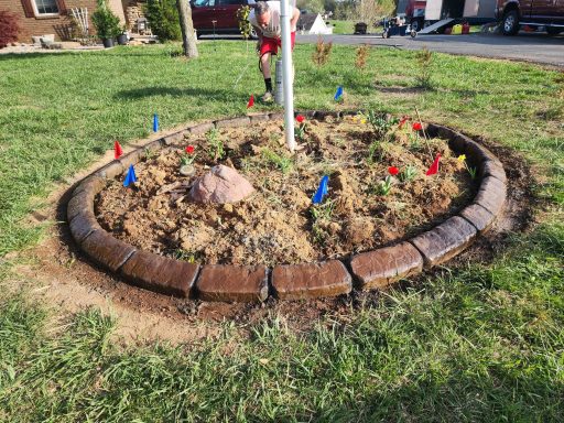 Flower bed with colorful markers, surrounded by a circular stone border.